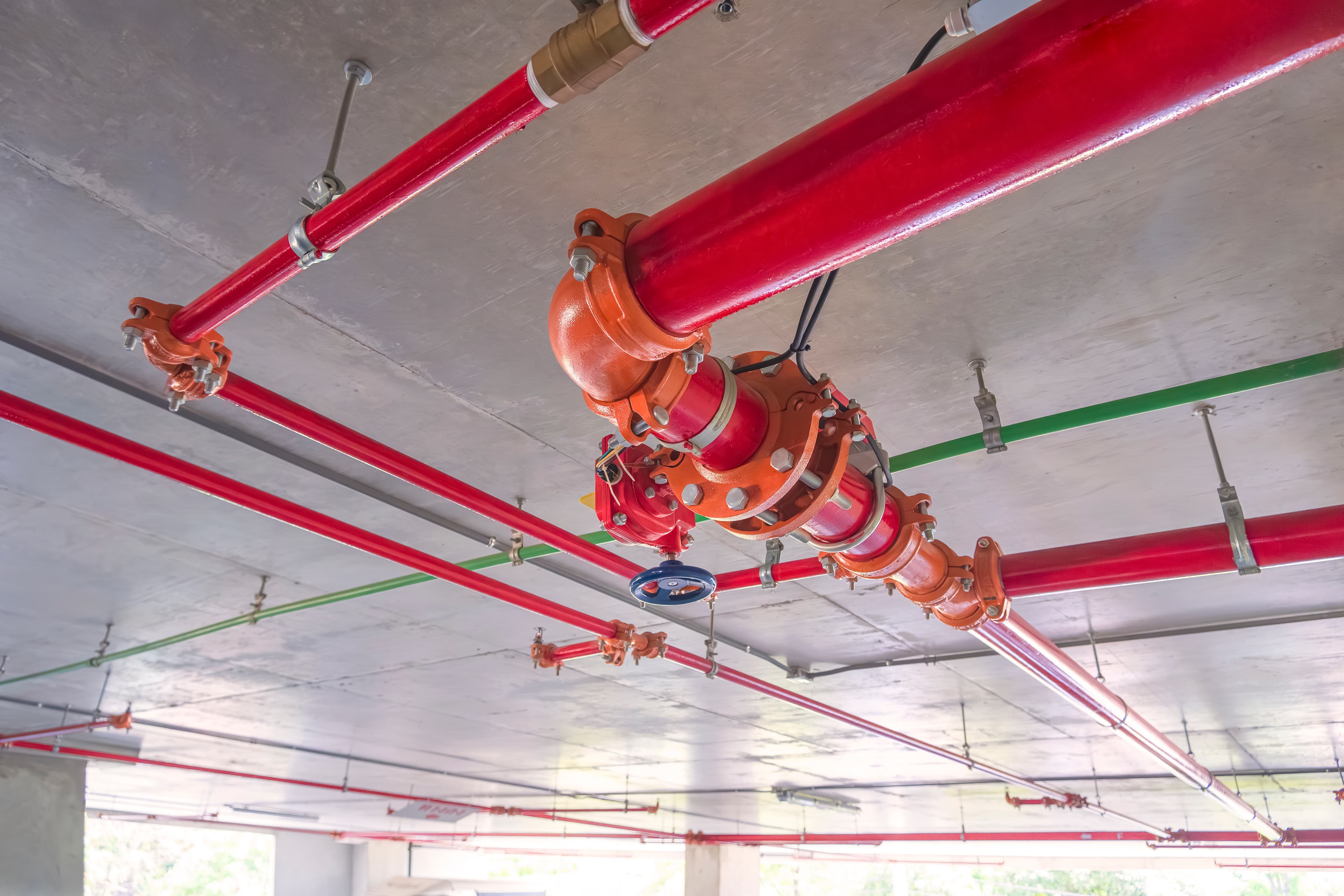 Red fire protective water pipeline system mounted on a concrete wall